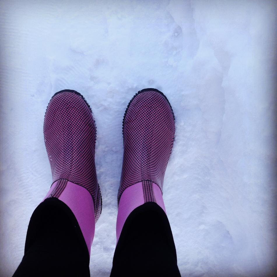 Photo of pink snow boots on the snow covered sidewalk 